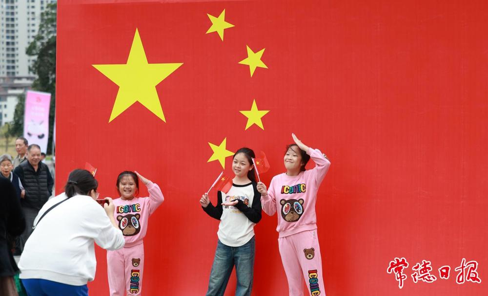 2024年10月1日，小游客们在常德河街与国旗合影